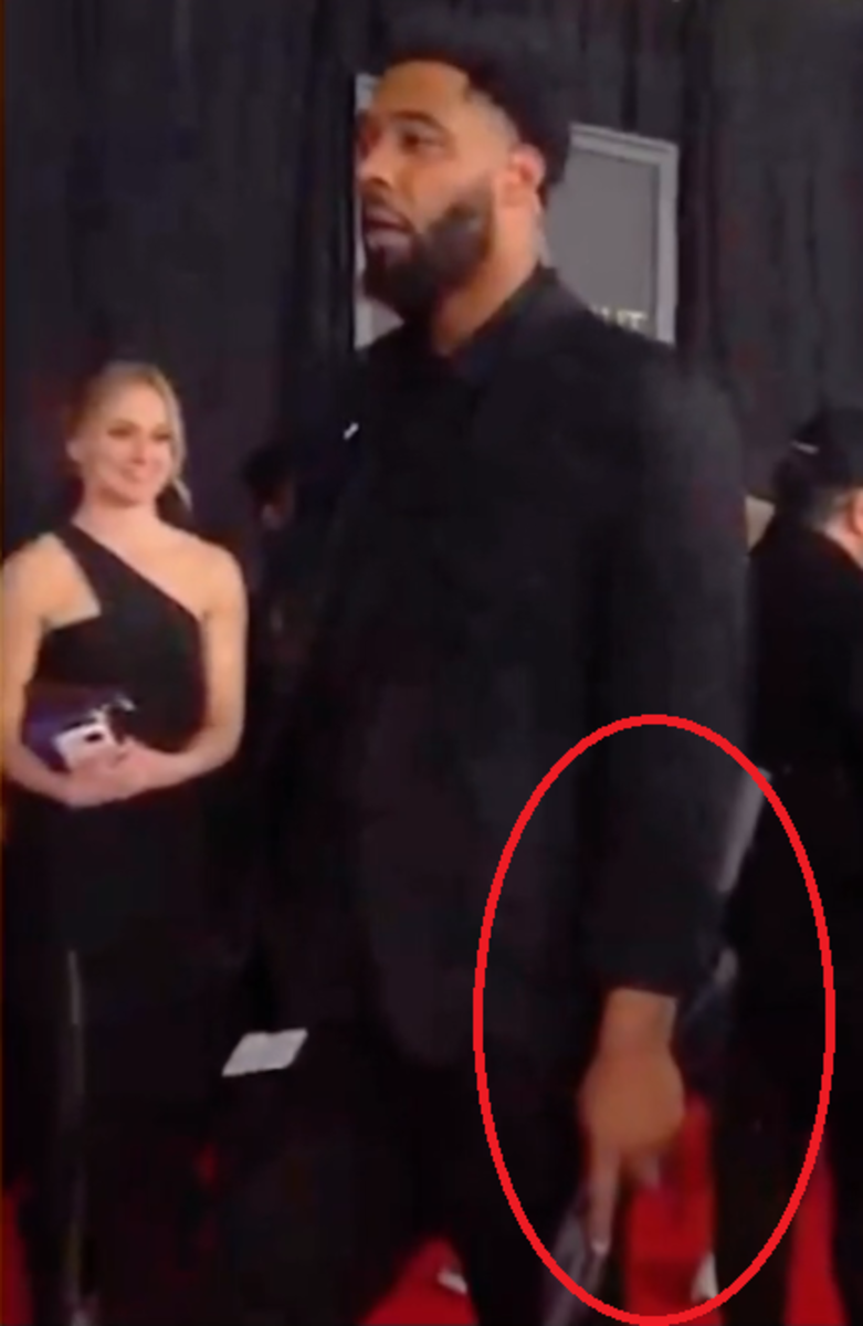 Miley Cyrus' bodyguard walking on the GRAMMYs' red carpet holding an umbrella, Photo Credit: alienthemartian/youtube